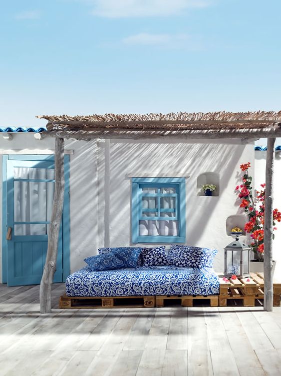 Mediterranean style sitting area in blues and whites with plush pillows, lanterns and colorful plants